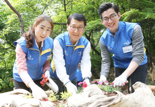 위성호 신한카드 대표(가운데)가 7일 오전 서울 남산공원 내 장충 유아 숲체험장에서 신입사원들과 함께 화분에 꽃을 심고 있다.